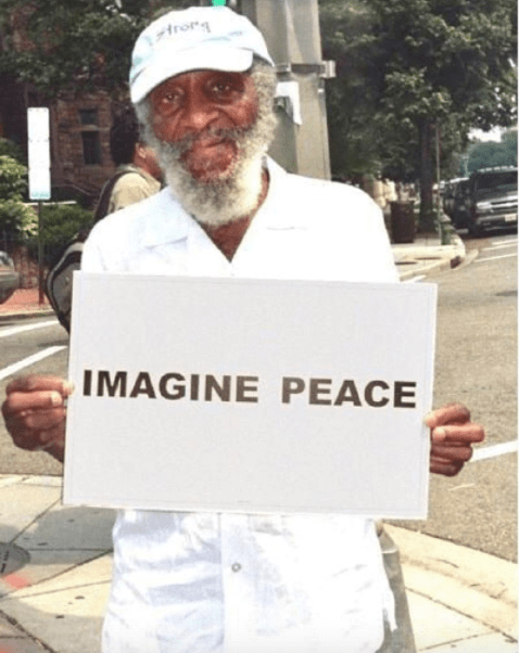DICK GREGORY, HOLDING A PEACE SIGN